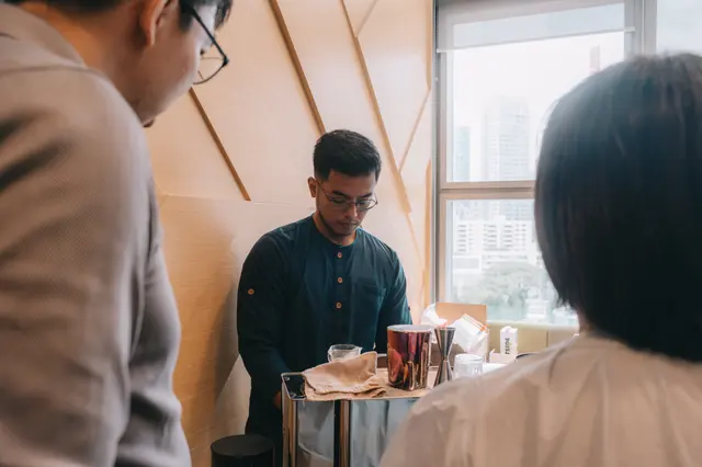 A Brewprint barista preparing coffee at a small cart while guests look on