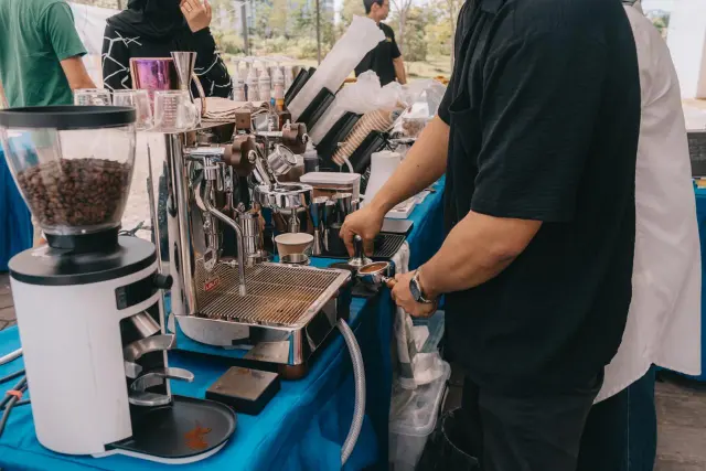 A Brewprint barista tamping espresso next to the grinder and espresso machine at the bazaar stall