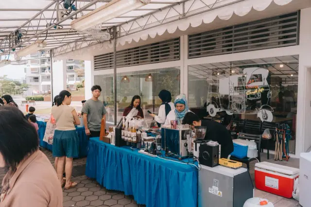 The Brewprint stall with a blue table skirt outside LemonGrass Restaurant, with customers waiting and the team preparing drinks