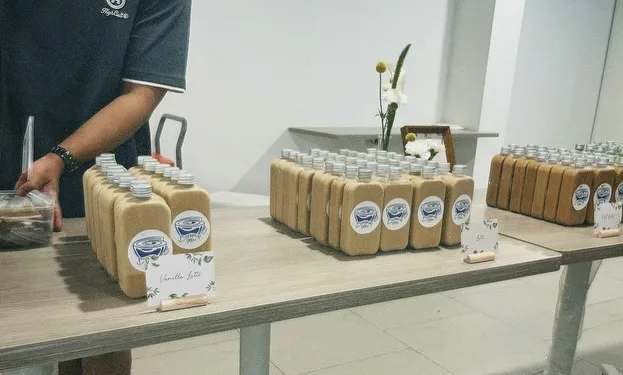 A Brewprint team member setting out bottled vanilla lattes on the door-gift table